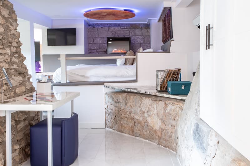 Modern interior of a cozy room featuring a stone wall, a bed, and a small dining area.