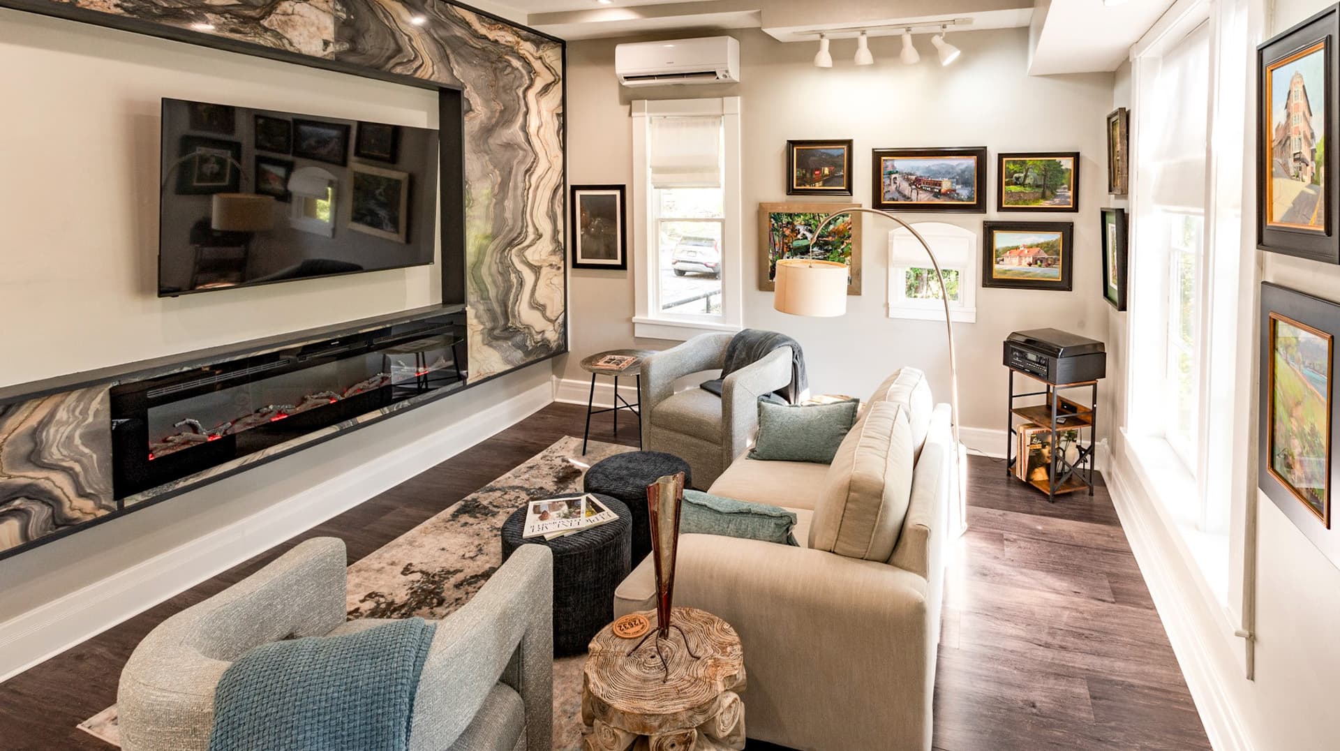 A modern living room featuring a sleek TV, artwork on the walls, and comfortable seating.