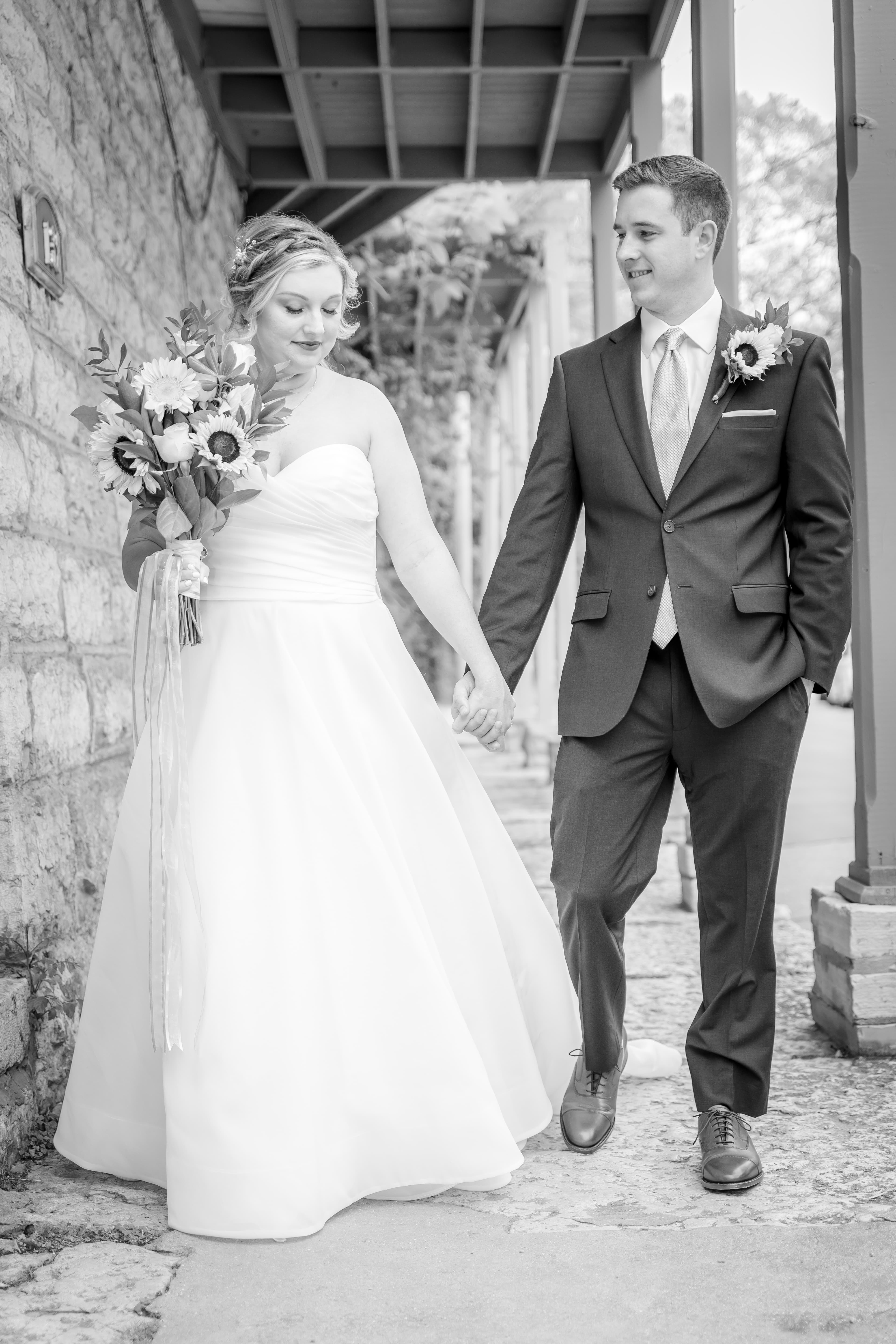 A bride and groom hold hands while walking together in a romantic setting.