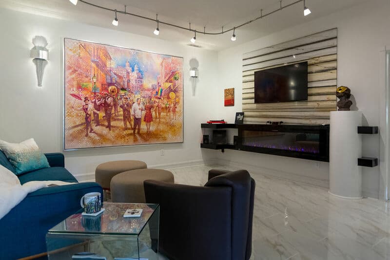 A modern living room featuring a colorful artwork, an electric fireplace, and a wall-mounted TV.