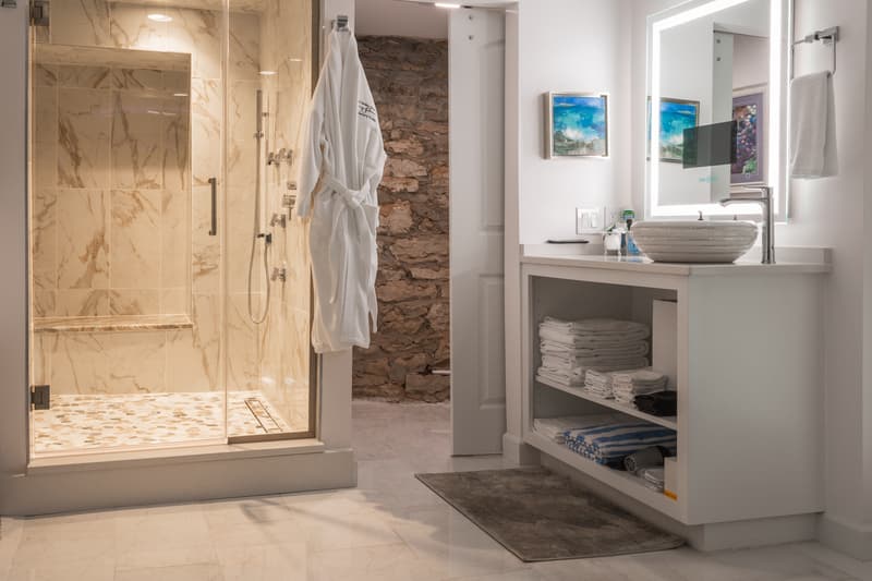 A modern bathroom featuring a glass shower, plush towels, and a sleek vanity.