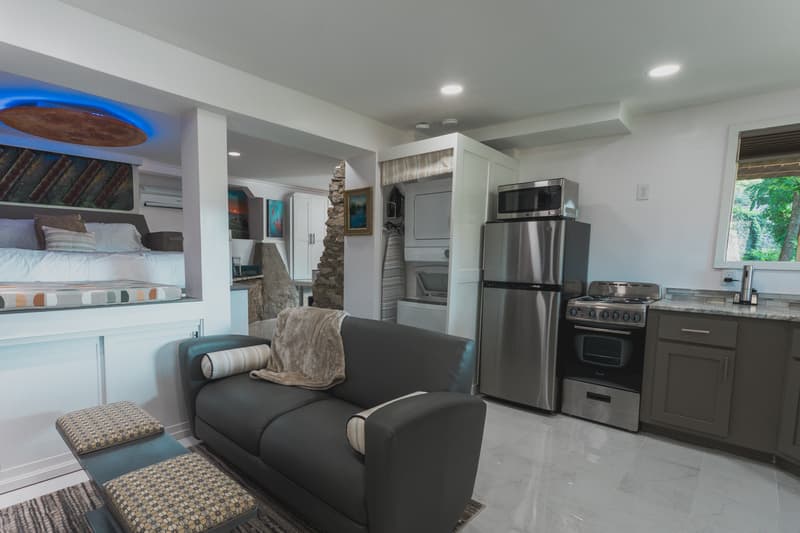 A modern, open-concept living space featuring a kitchenette, seating area, and a lofted bed area.