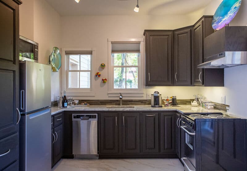 A modern kitchen featuring dark cabinetry, stainless steel appliances, and a granite countertop.
