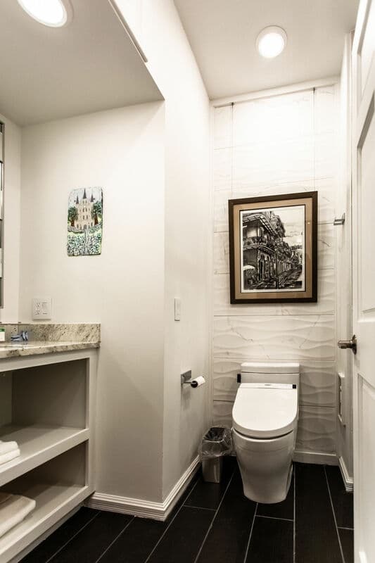 A modern bathroom featuring a toilet, sink, and artwork on the walls.