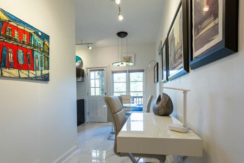 A bright hallway featuring a modern desk, artwork on the walls, and a view of a door leading to an outdoor space.