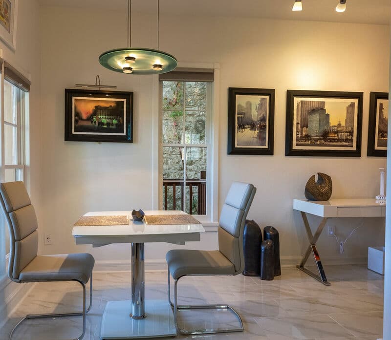 Modern dining area with a glass table, stylish chairs, and framed artwork on the walls.
