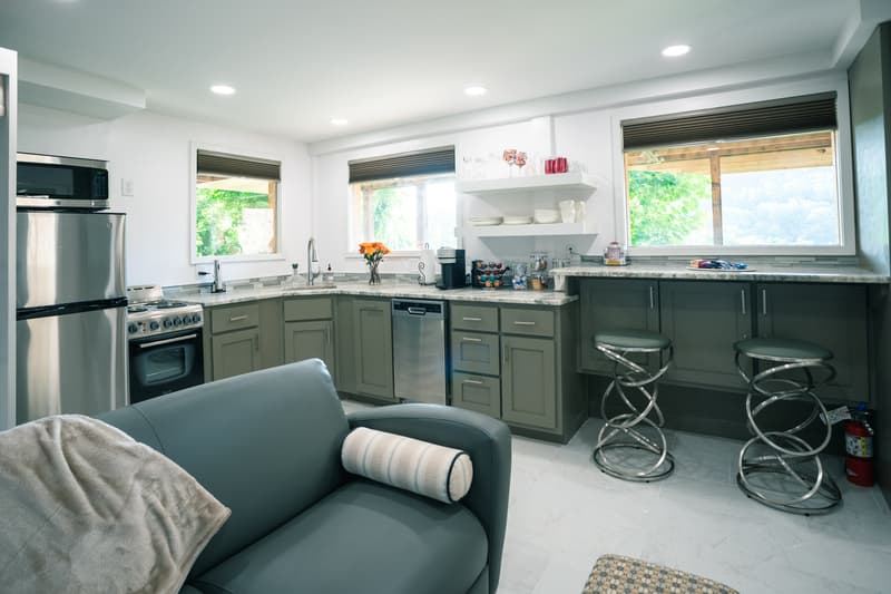 Modern kitchen with stainless steel appliances, gray cabinetry, and a cozy seating area.